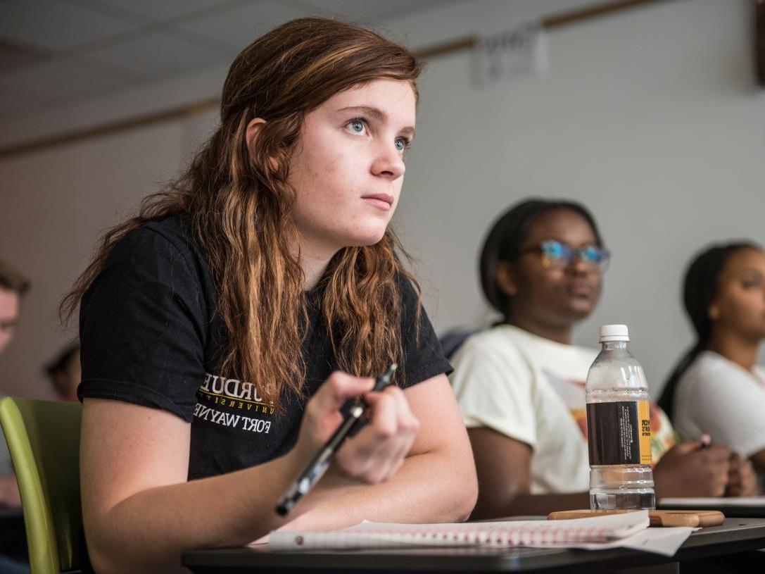 Student taking notes wears Purdue Fort Wayne shirt.